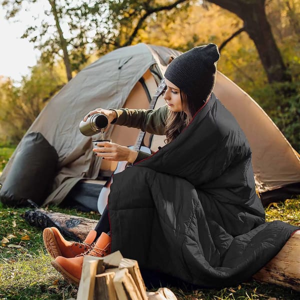 Black wearable camping blanket in a campsite setting