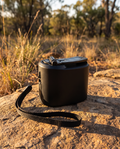 Black manual hand-crank USB charger on a flat rock at an Australian campsite at golden hour